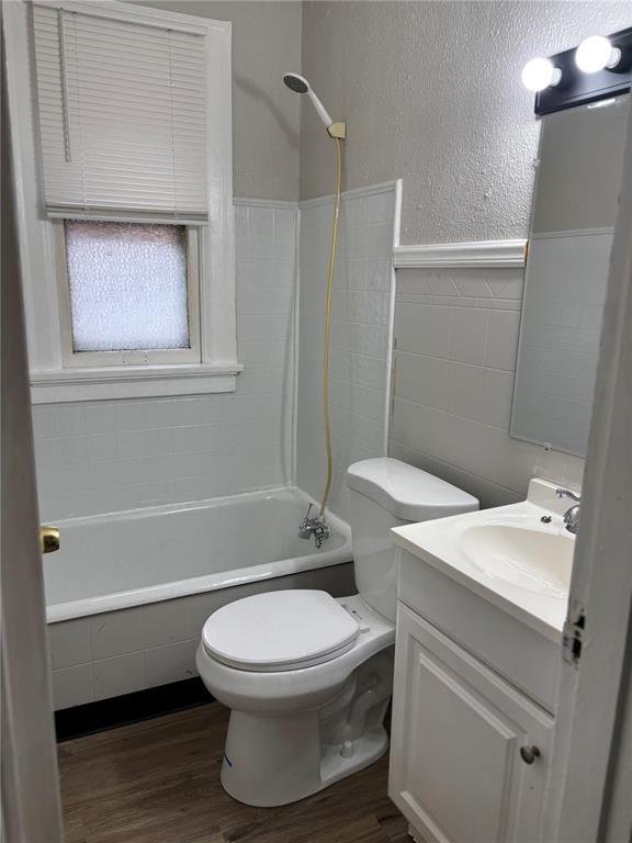 8324 Strathmore Pl, Jennings, MO 63136 - bathroom featuring wood finished floors, toilet, tile walls, vanity, and  shower combination