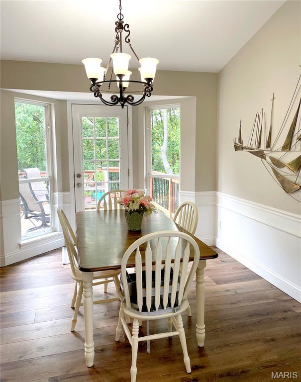 259 Jacob Ln, Ballwin, MO 63021 - dining area featuring a chandelier, healthy amount of natural light, a wainscoted wall, and wood finished floors