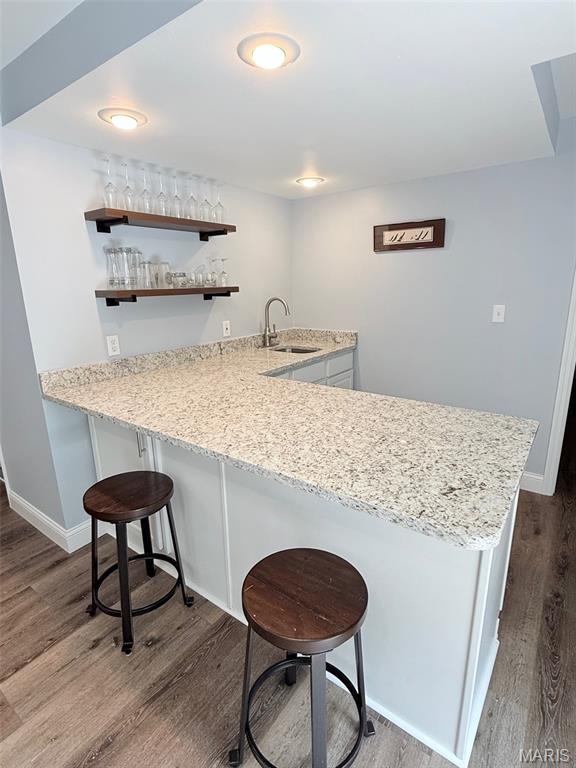 259 Jacob Ln, Ballwin, MO 63021 - kitchen featuring a peninsula, a sink, dark wood-style floors, and a kitchen bar
