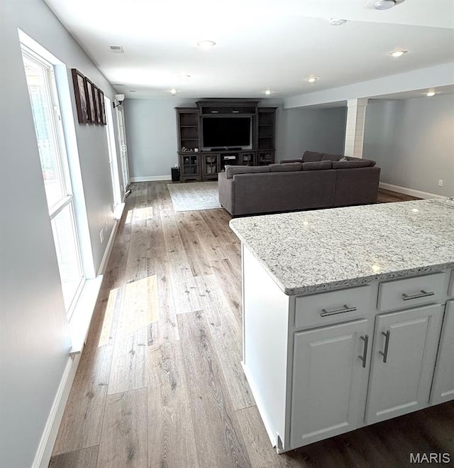 259 Jacob Ln, Ballwin, MO 63021 - kitchen with light wood-style floors, light stone countertops, baseboards, and white cabinets