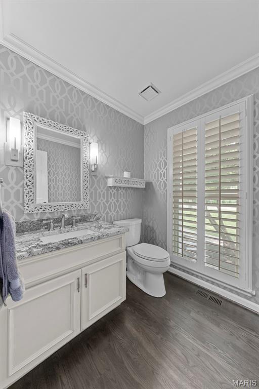 16434 Wilson Farm Dr, Chesterfield, MO 63005 - bathroom featuring crown molding, toilet, vanity, wood finished floors, and wallpapered walls
