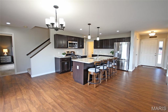 1030 Remington Dr, Imperial, MO 63052 - kitchen featuring stainless steel appliances, a kitchen breakfast bar, a chandelier, an island with sink, and dark wood finished floors