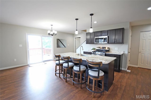 1030 Remington Dr, Imperial, MO 63052 - kitchen featuring stainless steel appliances, dark wood-style floors, light stone countertops, an island with sink, and a chandelier