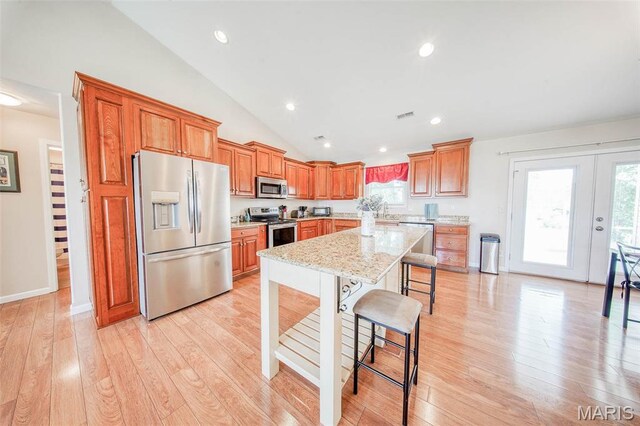11195 Lexington Ln, Rolla, MO 65401 - kitchen with stainless steel appliances, lofted ceiling, a kitchen bar, brown cabinets, and light wood-type flooring
