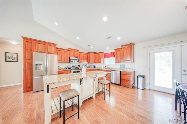 11195 Lexington Ln, Rolla, MO 65401 - kitchen featuring appliances with stainless steel finishes, a kitchen bar, brown cabinets, light wood finished floors, and high vaulted ceiling