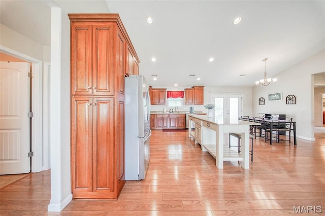 11195 Lexington Ln, Rolla, MO 65401 - kitchen with appliances with stainless steel finishes, a breakfast bar area, brown cabinetry, a sink, and light wood-style flooring