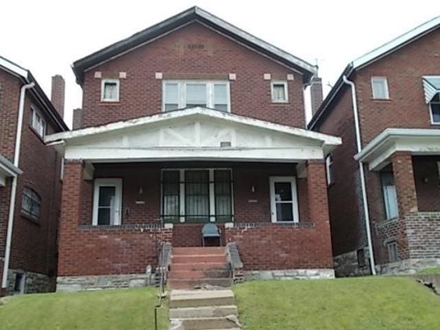 4308 N Euclid Ave, Saint Louis, MO 63115 - view of front of house with brick siding, covered porch, and a front lawn