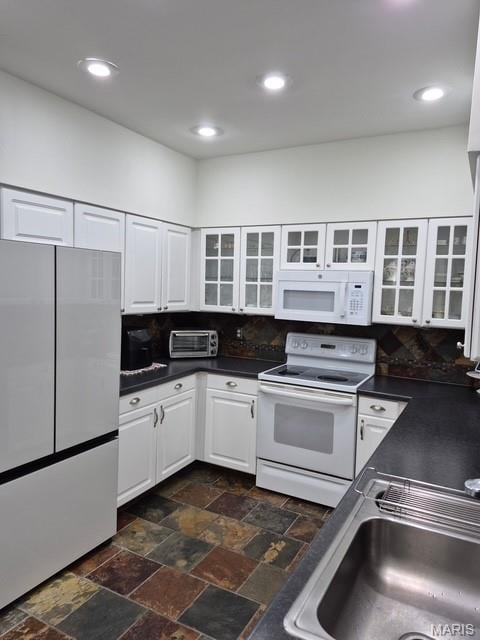 4465 W Pine Blvd Unit 15, Saint Louis, MO 63108 - kitchen featuring white appliances, dark countertops, white cabinets, dark stone finish flooring, and glass insert cabinets