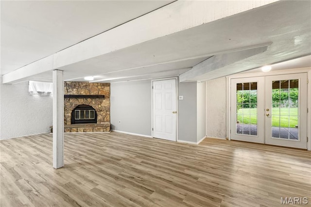894 Napoli Dr, Ballwin, MO 63021 - unfurnished living room with wood finished floors, french doors, a stone fireplace, and a textured wall