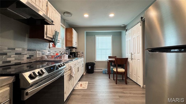 110 5th St, Park Hills, MO 63601 - kitchen featuring appliances with stainless steel finishes, exhaust hood, tasteful backsplash, light wood-style flooring, and recessed lighting