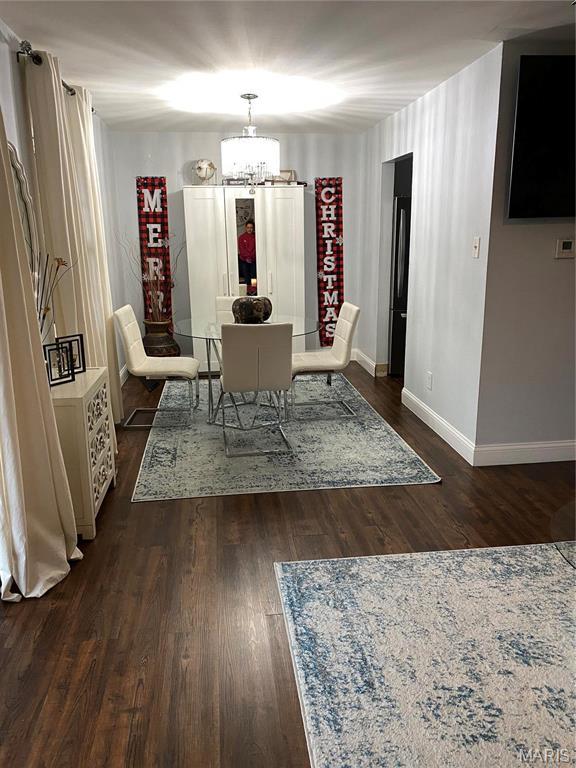 6966 Colonial Woods Dr Unit 62, Saint Louis, MO 63129 - dining room featuring baseboards, dark wood-style floors, and a chandelier