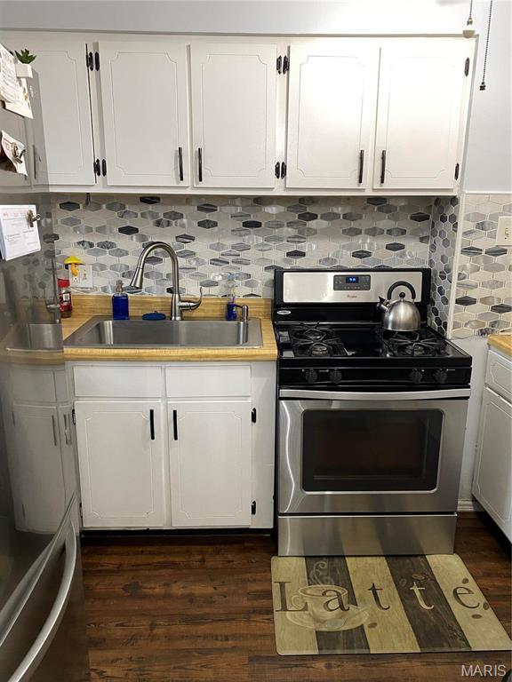 6966 Colonial Woods Dr Unit 62, Saint Louis, MO 63129 - kitchen with stainless steel range with gas cooktop, a sink, white cabinets, and backsplash
