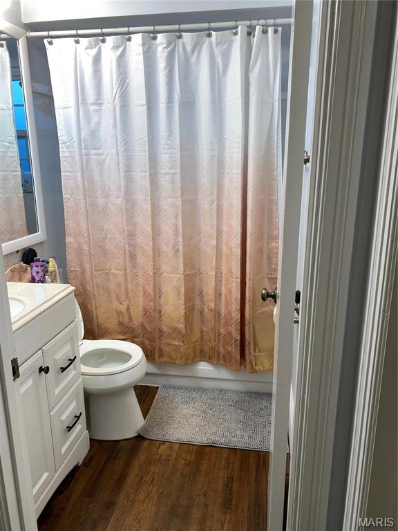 6966 Colonial Woods Dr Unit 62, Saint Louis, MO 63129 - bathroom with toilet, vanity, wood finished floors, and shower / bathtub combination with curtain
