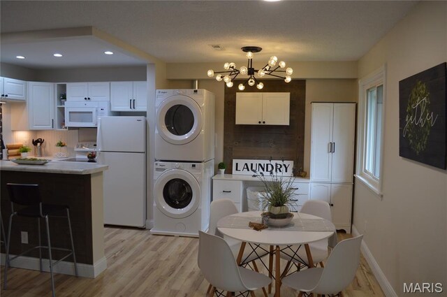 115 Lemans Ct Unit 115, Lake St Louis, MO 63367 - kitchen featuring white appliances, stacked washer / drying machine, a chandelier, backsplash, and white cabinets