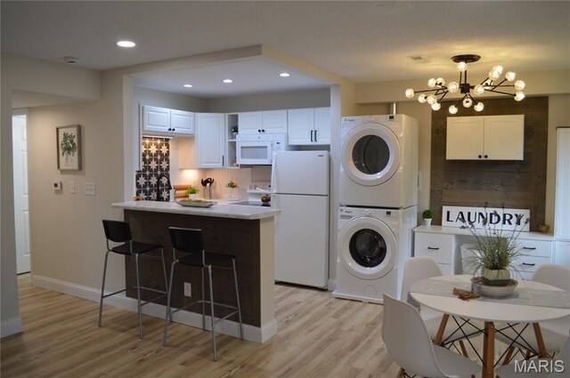 115 Lemans Ct Unit 115, Lake St Louis, MO 63367 - kitchen with stacked washer and clothes dryer, white appliances, tasteful backsplash, a peninsula, and light wood-type flooring