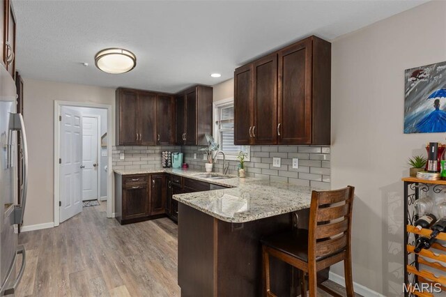 248 Prairie Grass Rd, Chatham, IL 62629 - kitchen with a sink, stainless steel refrigerator, light wood-style flooring, baseboards, and a peninsula
