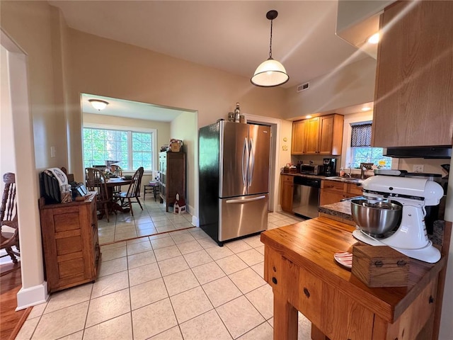 4001 W Ely Rd, Hannibal, MO 63401 - kitchen with stainless steel appliances, dark countertops, light tile patterned floors, pendant lighting, and brown cabinetry