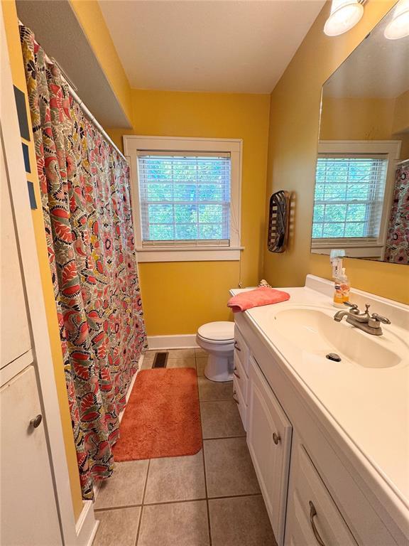 4001 W Ely Rd, Hannibal, MO 63401 - bathroom featuring toilet, vanity, tile patterned floors, curtained shower, and baseboards
