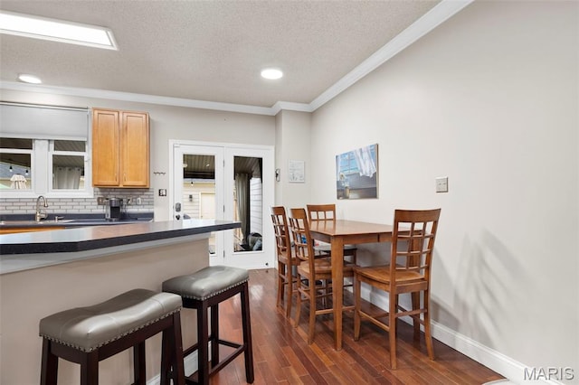 3216 Domain St, Saint Charles, MO 63301 - kitchen featuring a kitchen breakfast bar, dark countertops, ornamental molding, backsplash, and a textured ceiling