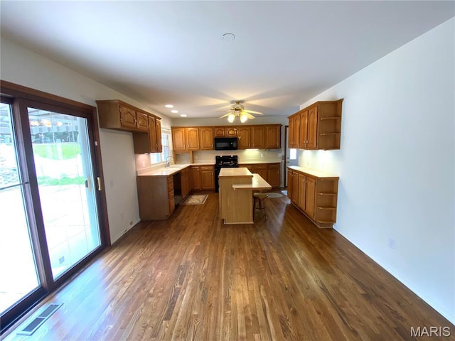 2287 Woodgrass Dr, Overland, MO 63114 - kitchen with dark wood finished floors, range, black microwave, open shelves, and healthy amount of natural light