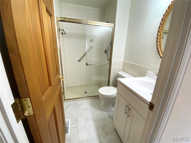 2287 Woodgrass Dr, Overland, MO 63114 - full bathroom with marble look tile flooring, vanity, toilet, a stall shower, and tile walls