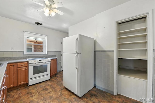 6912 Hampton Ave, Saint Louis, MO 63109 - kitchen featuring white appliances, tile walls, brown cabinetry, ceiling fan, and wainscoting