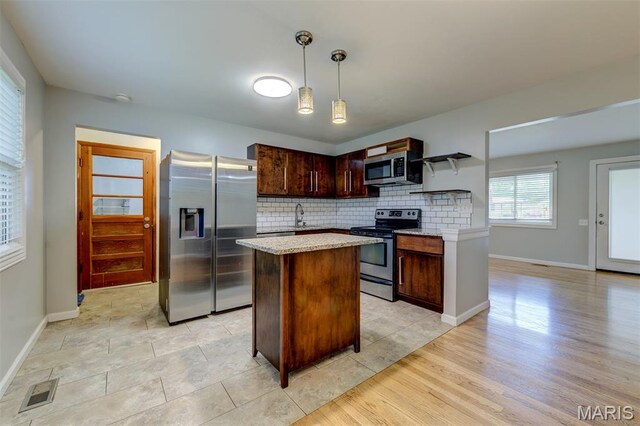36 Huck Finn Dr, Saint Charles, MO 63303 - kitchen featuring appliances with stainless steel finishes, tasteful backsplash, open shelves, a center island, and decorative light fixtures