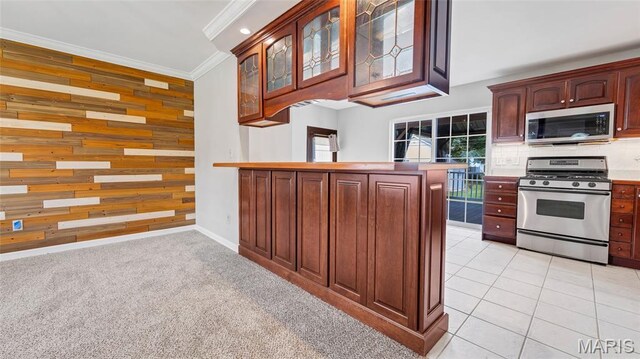 995 Sherman Ln, Florissant, MO 63031 - kitchen featuring stainless steel appliances, wood walls, ornamental molding, a peninsula, and glass insert cabinets