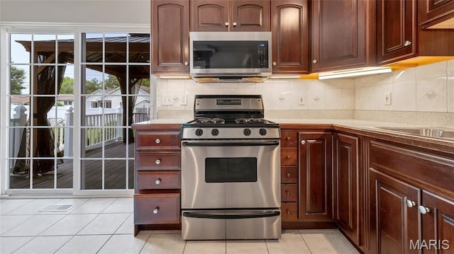 995 Sherman Ln, Florissant, MO 63031 - kitchen featuring stainless steel appliances, light countertops, light tile patterned flooring, and decorative backsplash