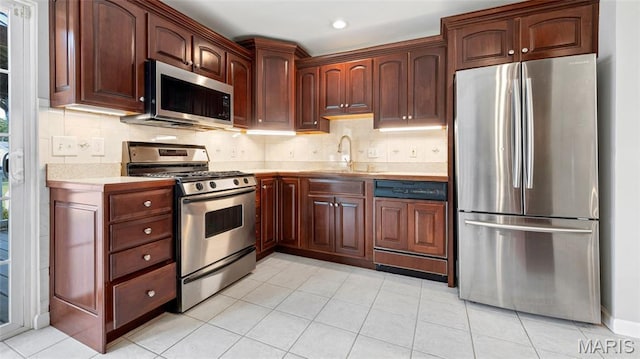 995 Sherman Ln, Florissant, MO 63031 - kitchen with stainless steel appliances, light countertops, a sink, backsplash, and recessed lighting