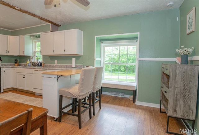 870 Walnut St, Newburg, MO 65550 - kitchen with dishwasher, white cabinetry, a kitchen breakfast bar, light wood-style flooring, and light countertops