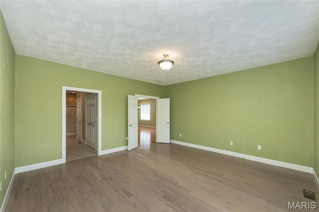 1812 Carrington Way, Belleville, IL 62226 - unfurnished bedroom featuring baseboards, wood finished floors, a textured ceiling, and a walk in closet