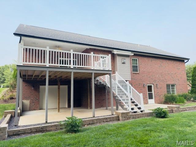 2063 Chesapeake Ave, Cape Girardeau, MO 63701 - rear view of property featuring a patio, an attached garage, brick siding, a wooden deck, and a lawn
