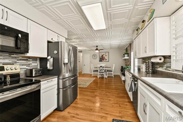 1522 S Oakland Ave, Bolivar, MO 65613 - kitchen featuring appliances with stainless steel finishes, an ornate ceiling, a ceiling fan, white cabinets, and decorative backsplash