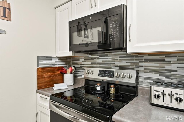 1522 S Oakland Ave, Bolivar, MO 65613 - kitchen with stainless steel range with electric stovetop, black microwave, white cabinetry, and tasteful backsplash