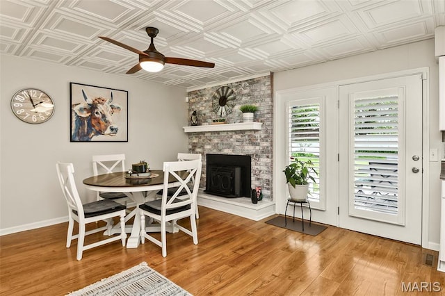 1522 S Oakland Ave, Bolivar, MO 65613 - dining area with ceiling fan, light wood-style floors, an ornate ceiling, a large fireplace, and baseboards