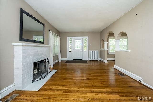 7041 Northmoor Dr, University City, MO 63105 - entrance foyer featuring radiator heating unit, wood finished floors, a fireplace, and arched walkways