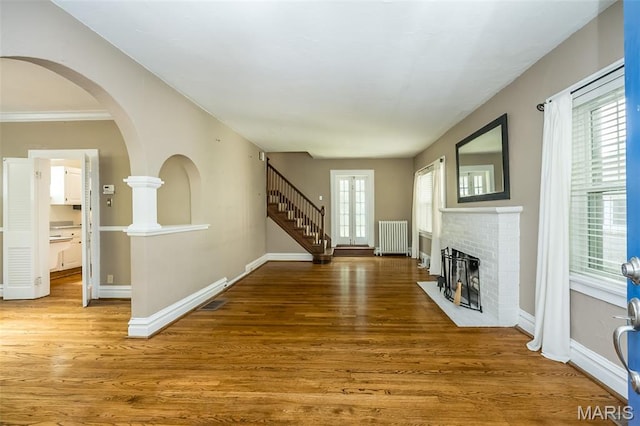 7041 Northmoor Dr, University City, MO 63105 - unfurnished living room featuring radiator heating unit, wood finished floors, and a brick fireplace