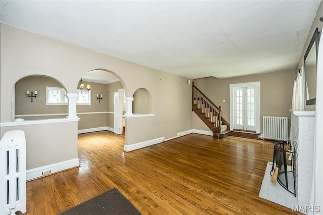 7041 Northmoor Dr, University City, MO 63105 - unfurnished living room with radiator, wood finished floors, arched walkways, and stairway