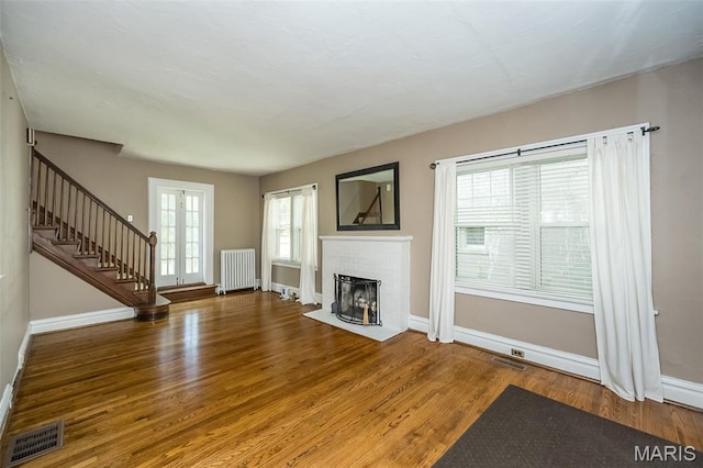 7041 Northmoor Dr, University City, MO 63105 - unfurnished living room with radiator, wood finished floors, stairway, a fireplace, and french doors