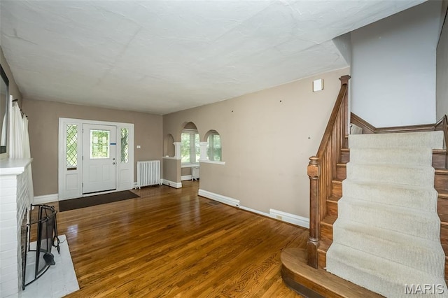 7041 Northmoor Dr, University City, MO 63105 - entrance foyer featuring radiator, stairway, wood finished floors, arched walkways, and baseboard heating