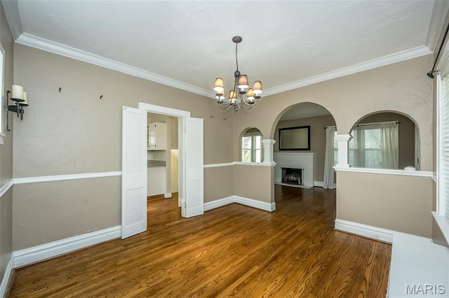 7041 Northmoor Dr, University City, MO 63105 - empty room with a chandelier, wood finished floors, crown molding, a fireplace, and arched walkways