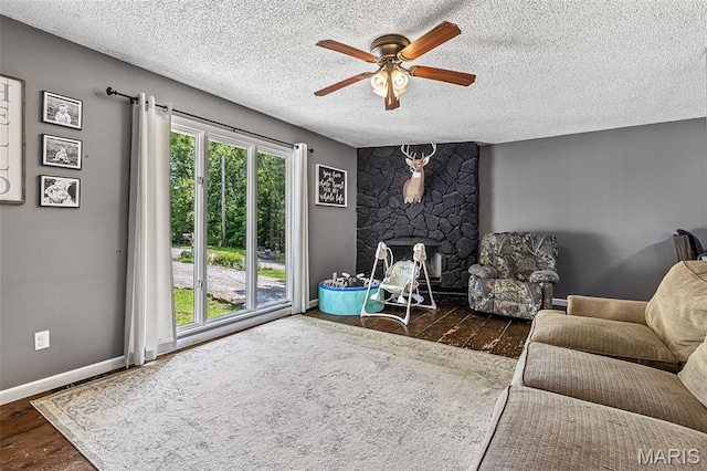 1764 Bourbon Dr, Bonne Terre, MO 63628 - living room featuring a ceiling fan, wood finished floors, a stone fireplace, a textured ceiling, and baseboards