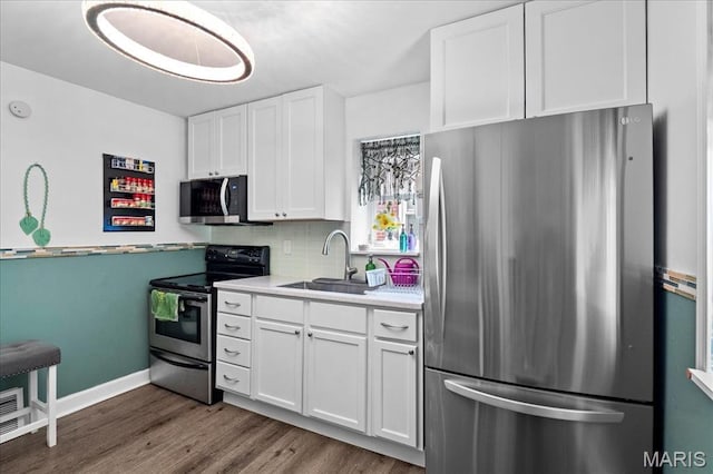 2929 Lincoln Ave, Saint Louis, MO 63121 - kitchen featuring stainless steel appliances, a sink, dark wood finished floors, white cabinets, and light countertops