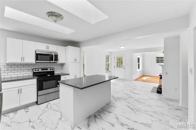 10735 Wurdack Ave, Saint Louis, MO 63114 - kitchen with appliances with stainless steel finishes, dark countertops, light marble finish floors, and white cabinets