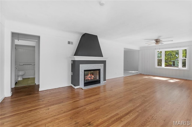 10735 Wurdack Ave, Saint Louis, MO 63114 - unfurnished living room with light wood finished floors, ceiling fan, and a multi sided fireplace
