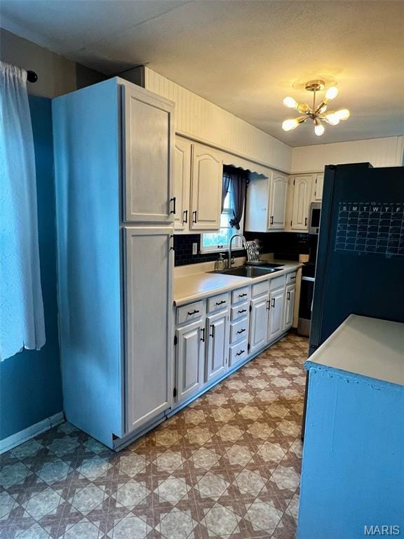 16 Wauneta Pl, Hannibal, MO 63401 - kitchen with light floors, a sink, a chandelier, freestanding refrigerator, and light countertops