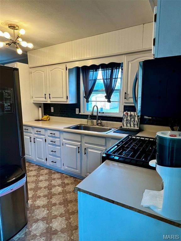 16 Wauneta Pl, Hannibal, MO 63401 - kitchen featuring a sink, black fridge, light floors, a chandelier, and white cabinets