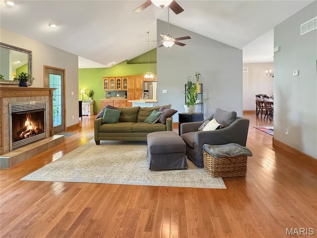 495 Oak Field Ct, Washington, MO 63090 - living room with light wood-style floors, a tile fireplace, ceiling fan, a chandelier, and high vaulted ceiling