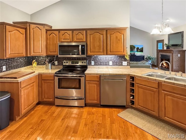 495 Oak Field Ct, Washington, MO 63090 - kitchen with appliances with stainless steel finishes, lofted ceiling, a sink, decorative backsplash, and tile countertops